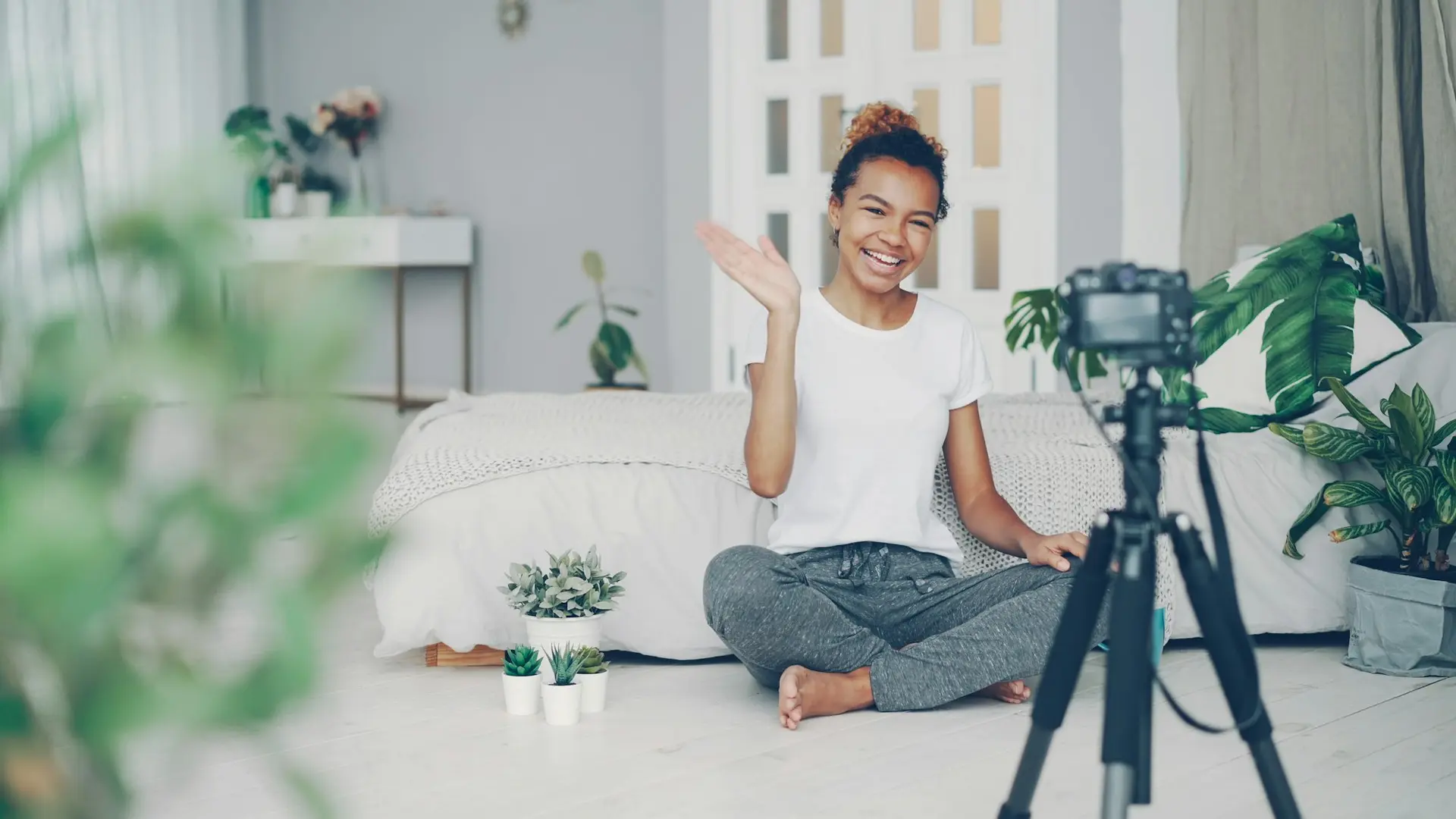 Young woman waves at camera in a room