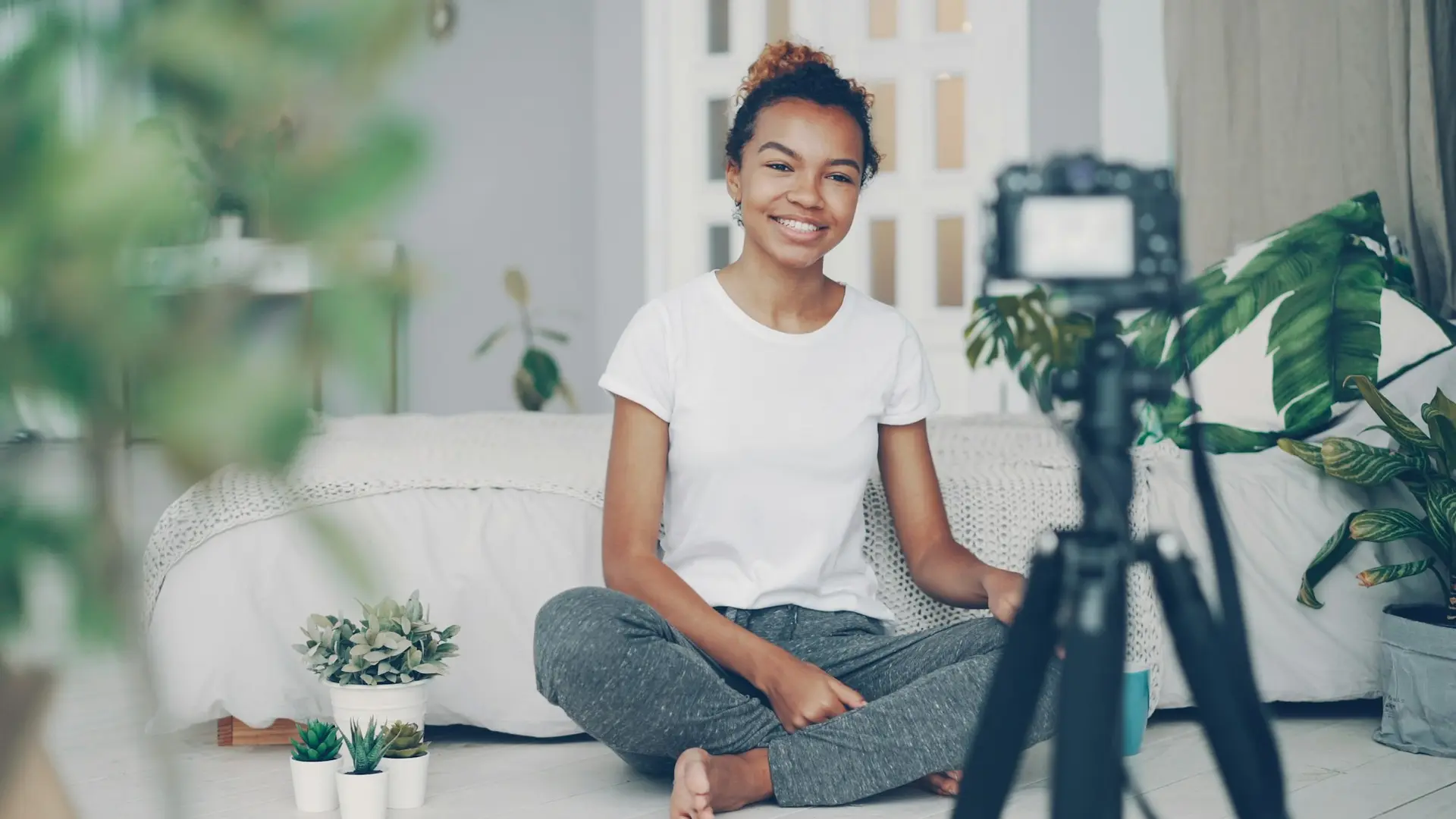 Young woman filming herself with a camera at home