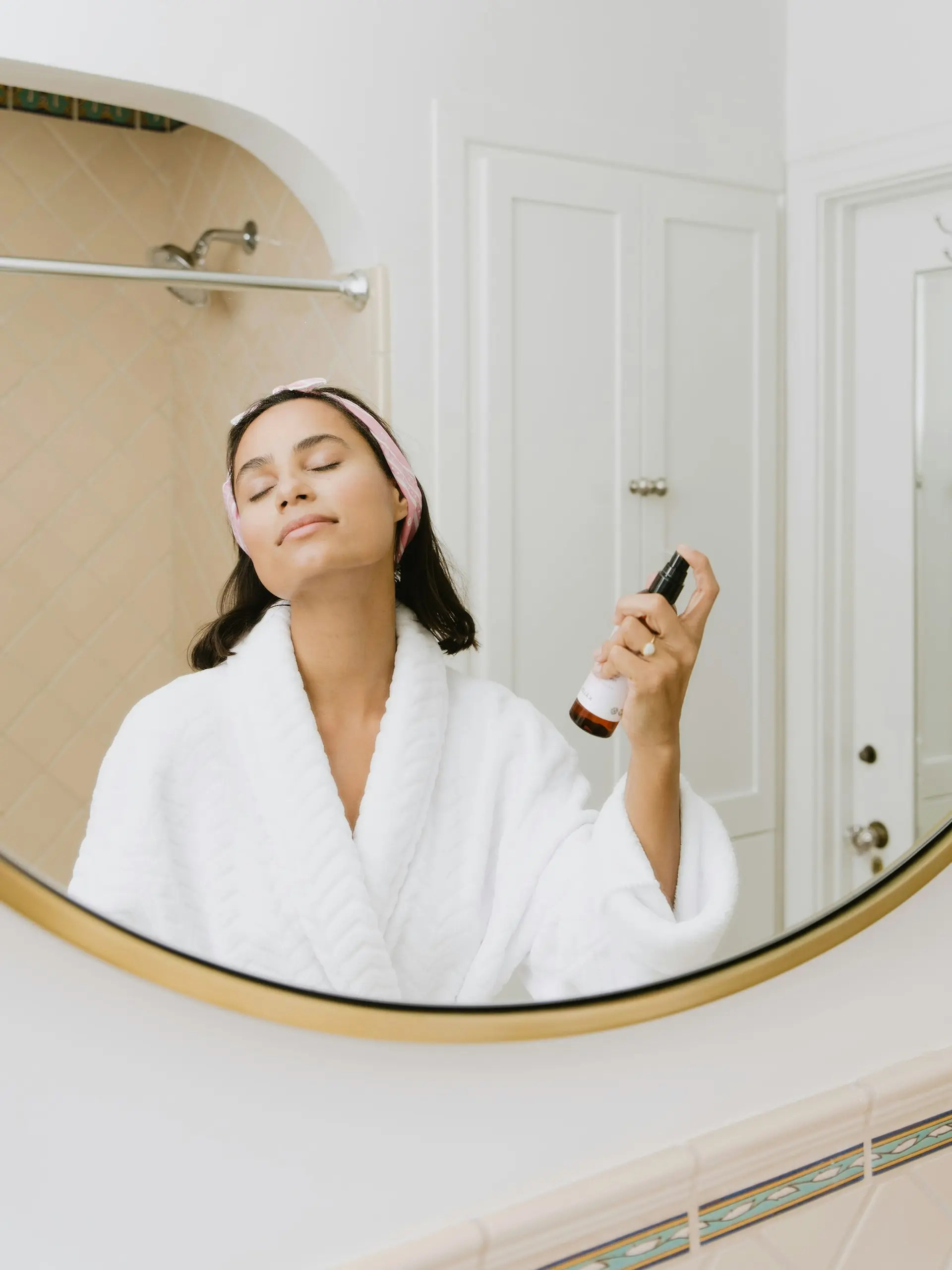 Woman spraying facial mist in a bathroom