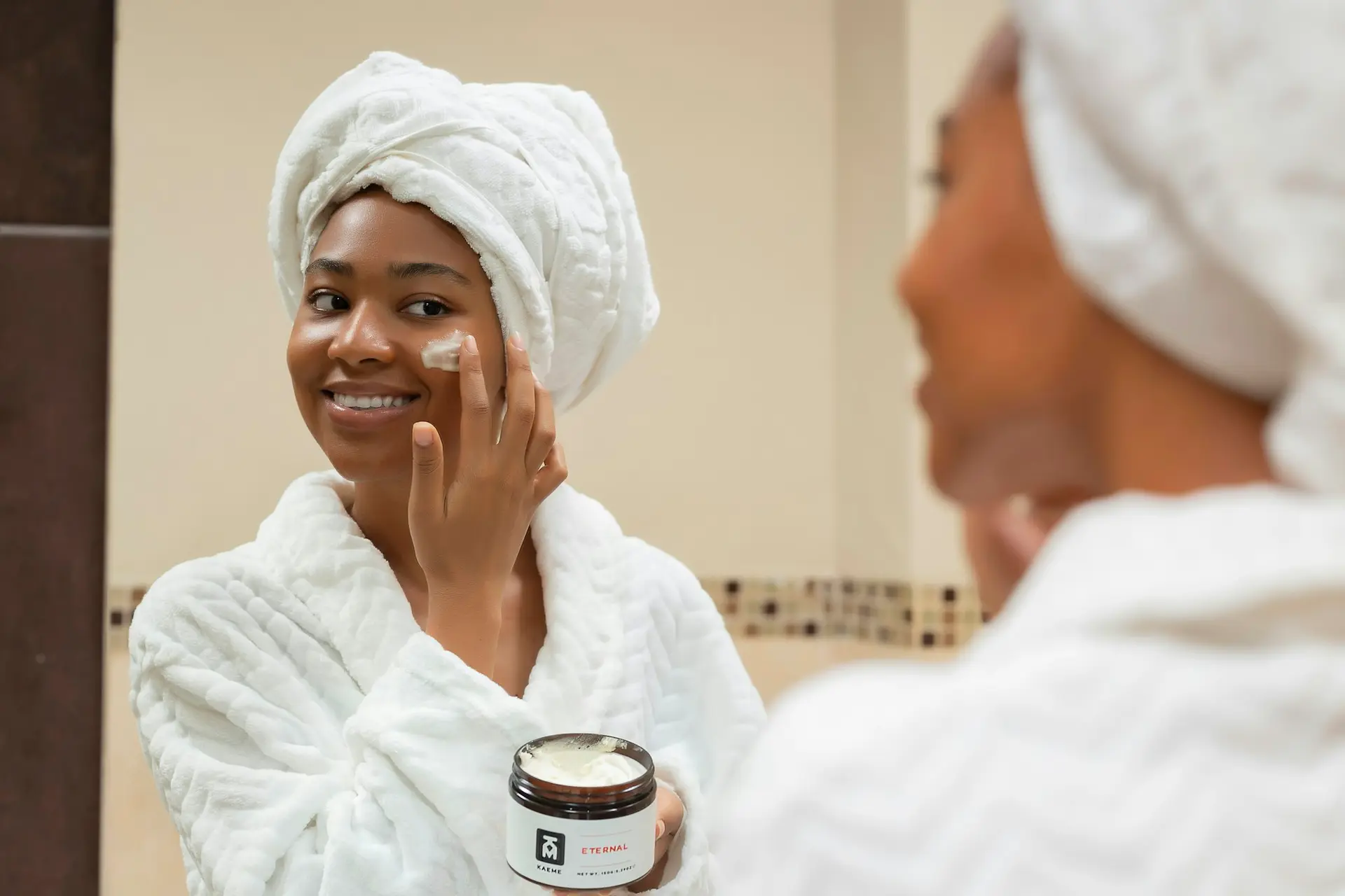 Woman in a towel with a jar of cream